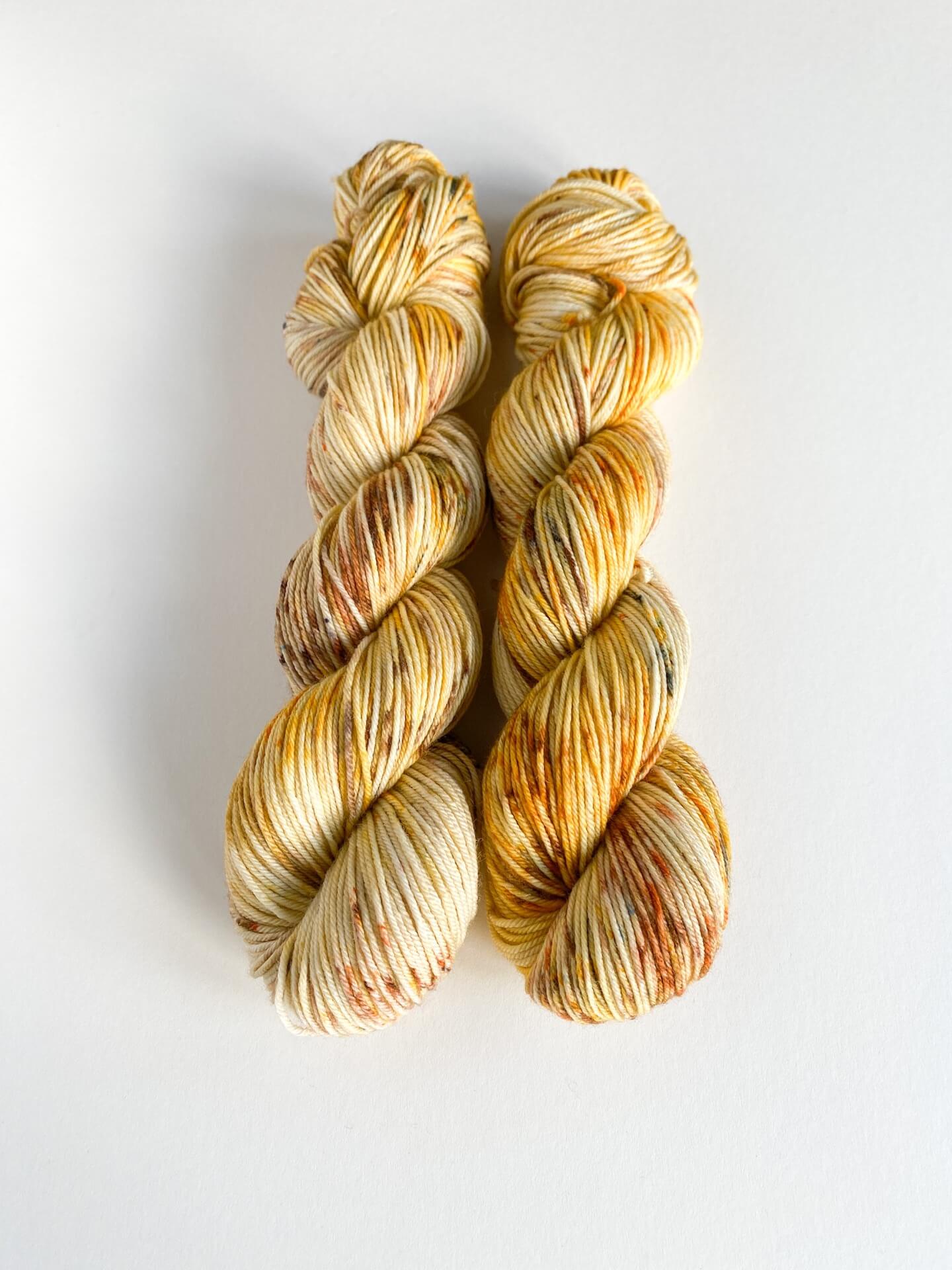 Yarn wound into two skeins. The yarn has been dyed with orange and brown dyes.
