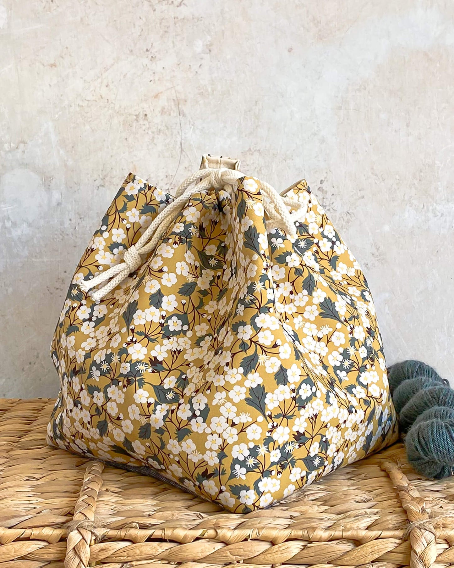 A project bag for knitting and crochet made from yellow Liberty of London fabric.