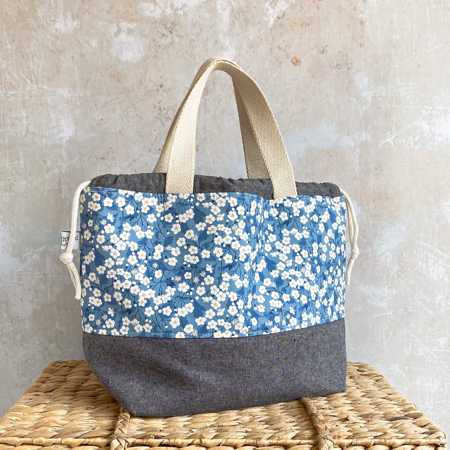 A side view of a large blue floral craft project bag designed to hold projects like sweaters and blankets.