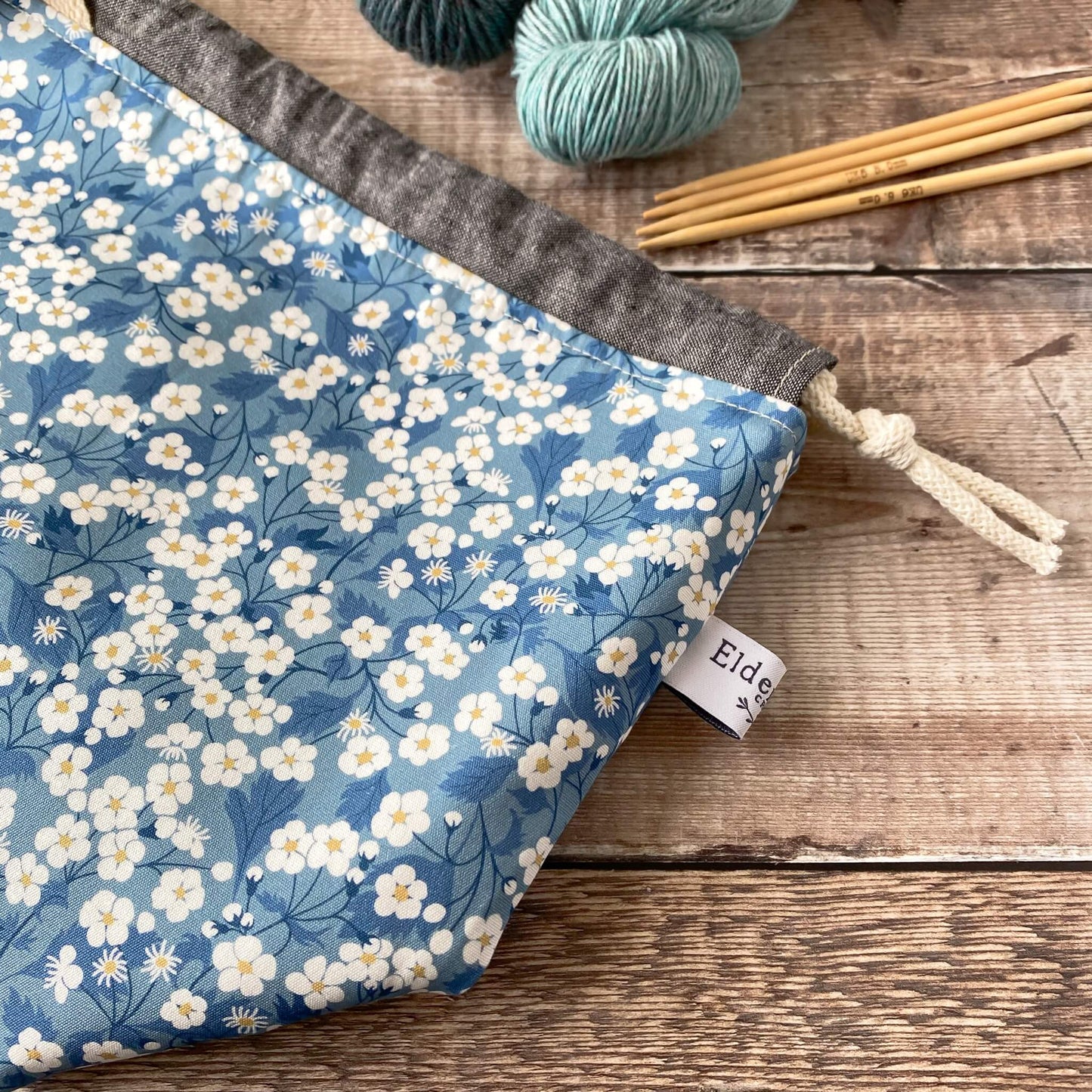 A close up of a craft project bag showing the detail of the blue floral Liberty of London fabric and the maker's label.