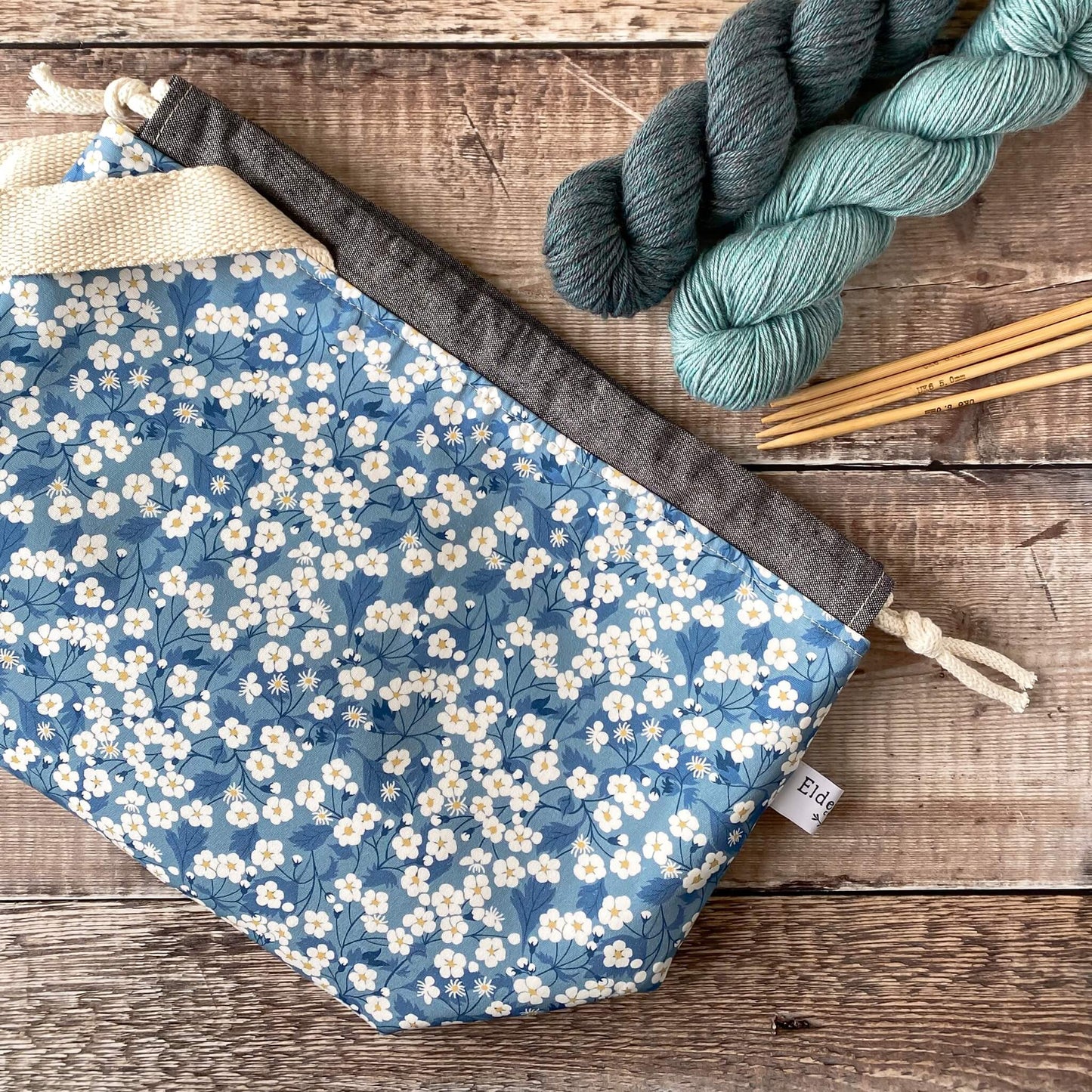 A flat lay of a medium sized blue floral project bag. The bag is designed for knitters and crocheters to keep their projects in.