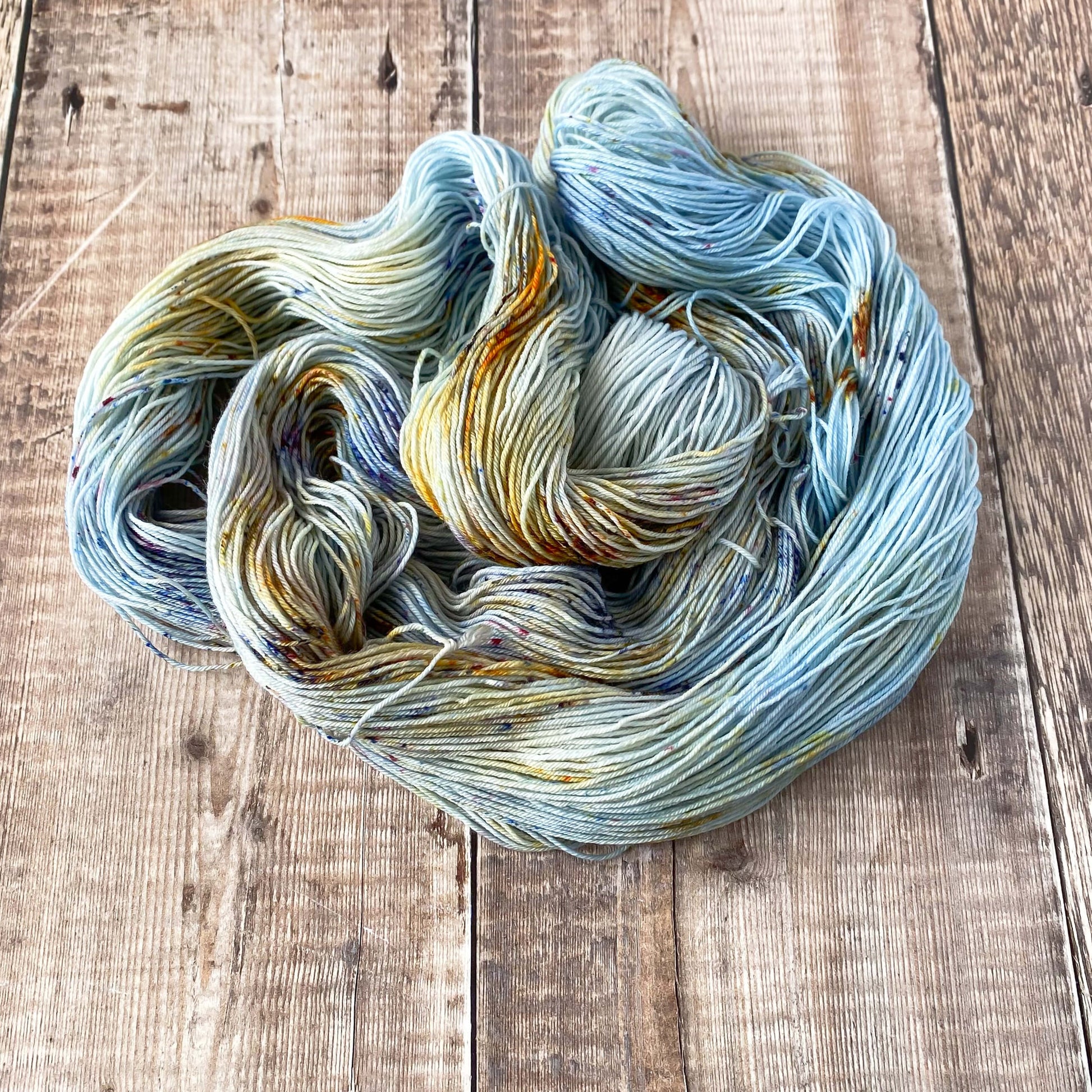 A coiled skein of hand dyed yarn in orange, blue and brown