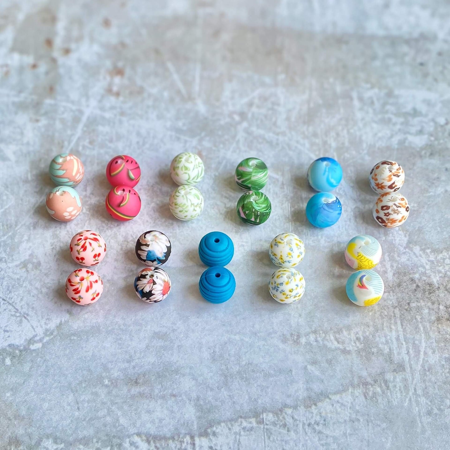 11 pairs of brightly coloured silicone balls sit in 2 rows on distressed plastered surface.