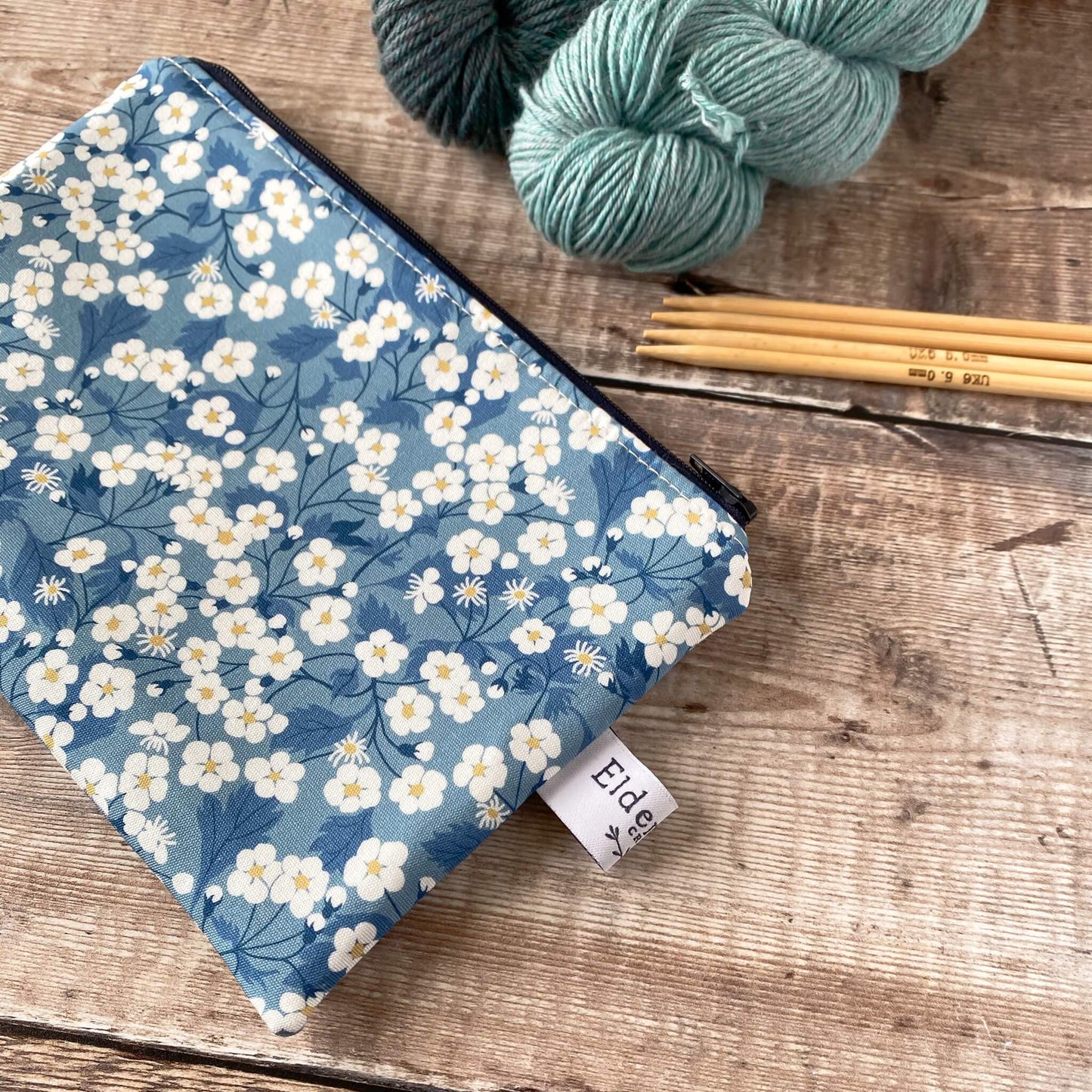 A close up of a blue notions pouch for knitting and crochet projects, made from a blue floral Liberty of London fabric.