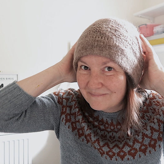 Emma, the host of the Eldenwood Craft knitting podcast, showing off the Leni hat, hand knit in beautiful brown hand dyed yarn