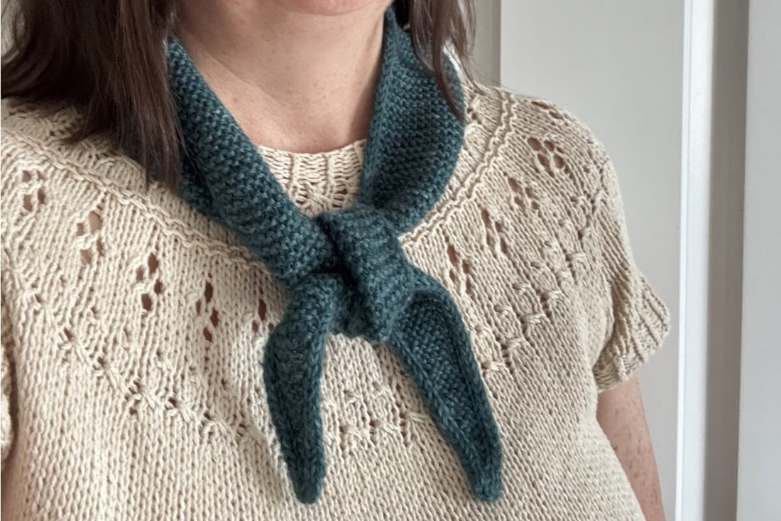 A green knitted Sophie Scarf worn with a handknit Ranunculus sweater 