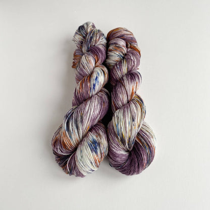 Yarn wound into two skeins. The yarn has been dyed with purple, blue and brown dyes. 