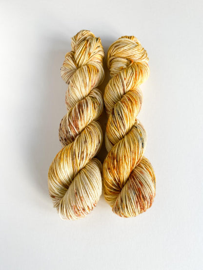 Yarn wound into two skeins. The yarn has been dyed with orange and brown dyes. 