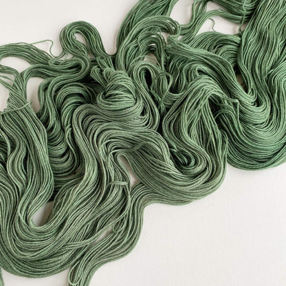 Forest green hand dyed yarn sits on a table top