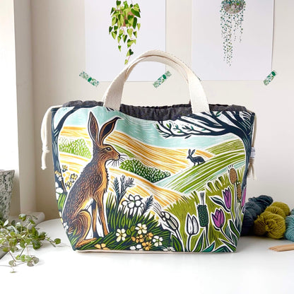 Fabric bag with nature-themed design featuring animals and plants on a white surface.