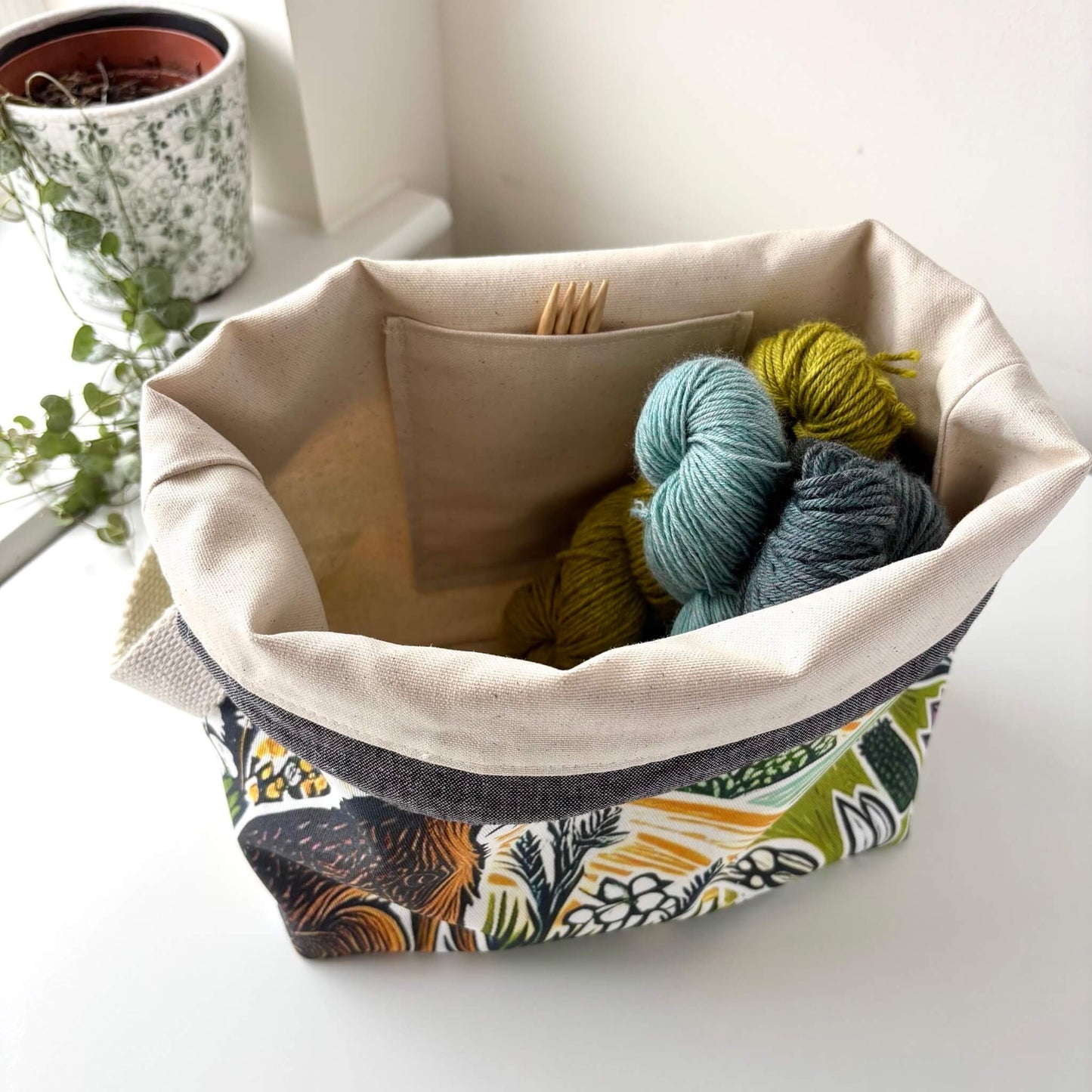 An open knitting project bag showing yarn and knitting needles tucked inside