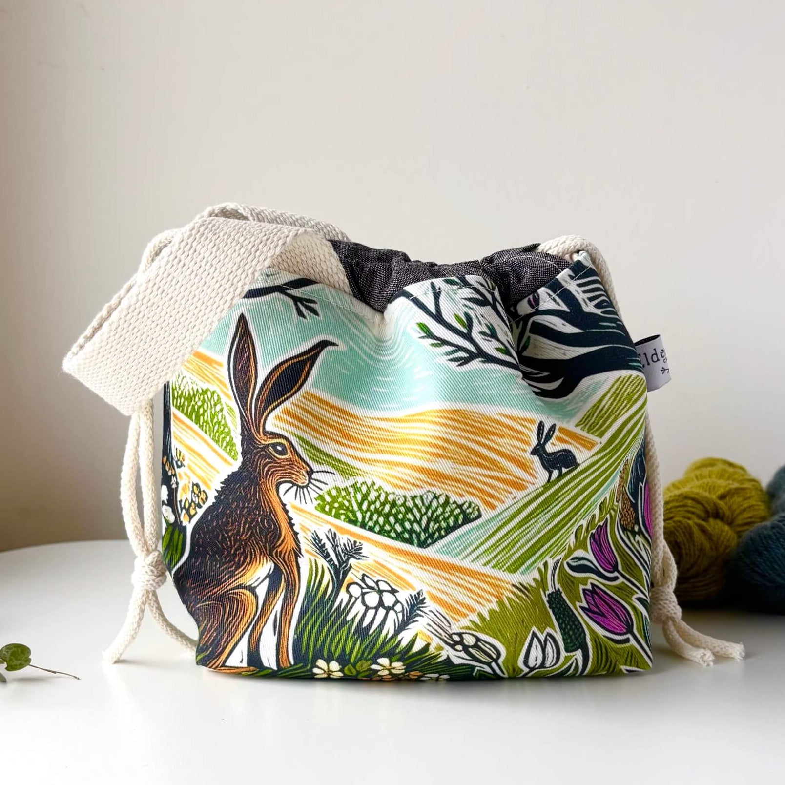 Drawstring bag with nature-themed design featuring animals and landscapes on a white surface.
