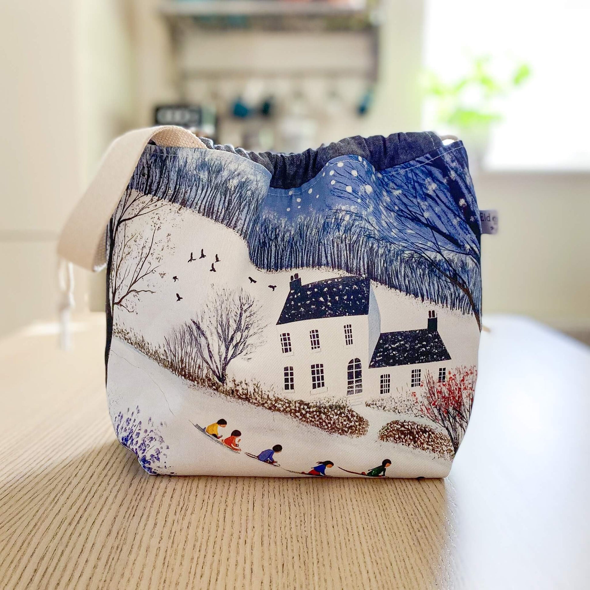 Handmade drawstring project bag with a winter country house print, designed for knitters and crocheters