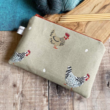 Load image into Gallery viewer, A small zippered pouch lies on a wooden table next to some yarn and knitting needles. The pouch is perfect for keeping knitting notions in and is made from a chicken print. Three chickens can be seen and each of them appears to have laid an egg. 