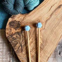 Load image into Gallery viewer, Robins Egg needle protectors to stop stitches escaping from knitting needles. A pair sit on a wooden table attached to knitting needles.