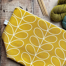 Load image into Gallery viewer, A sunshine yellow knitting project bag sits on a wooden table next to some skeins of yarn. 