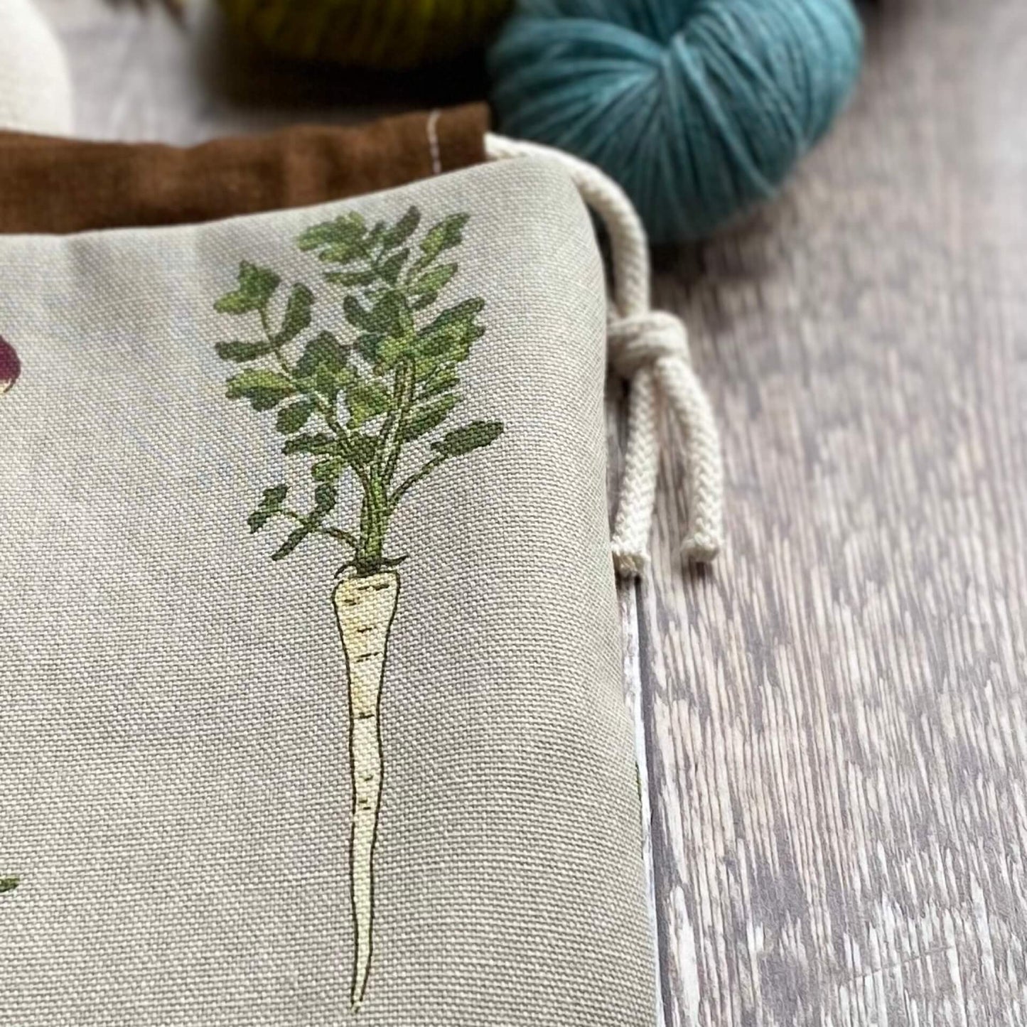 A close up of part of a handmade knitting project bag from the Root Veg collection. The close up shows part of the print in detail - a hand drawn parsnip